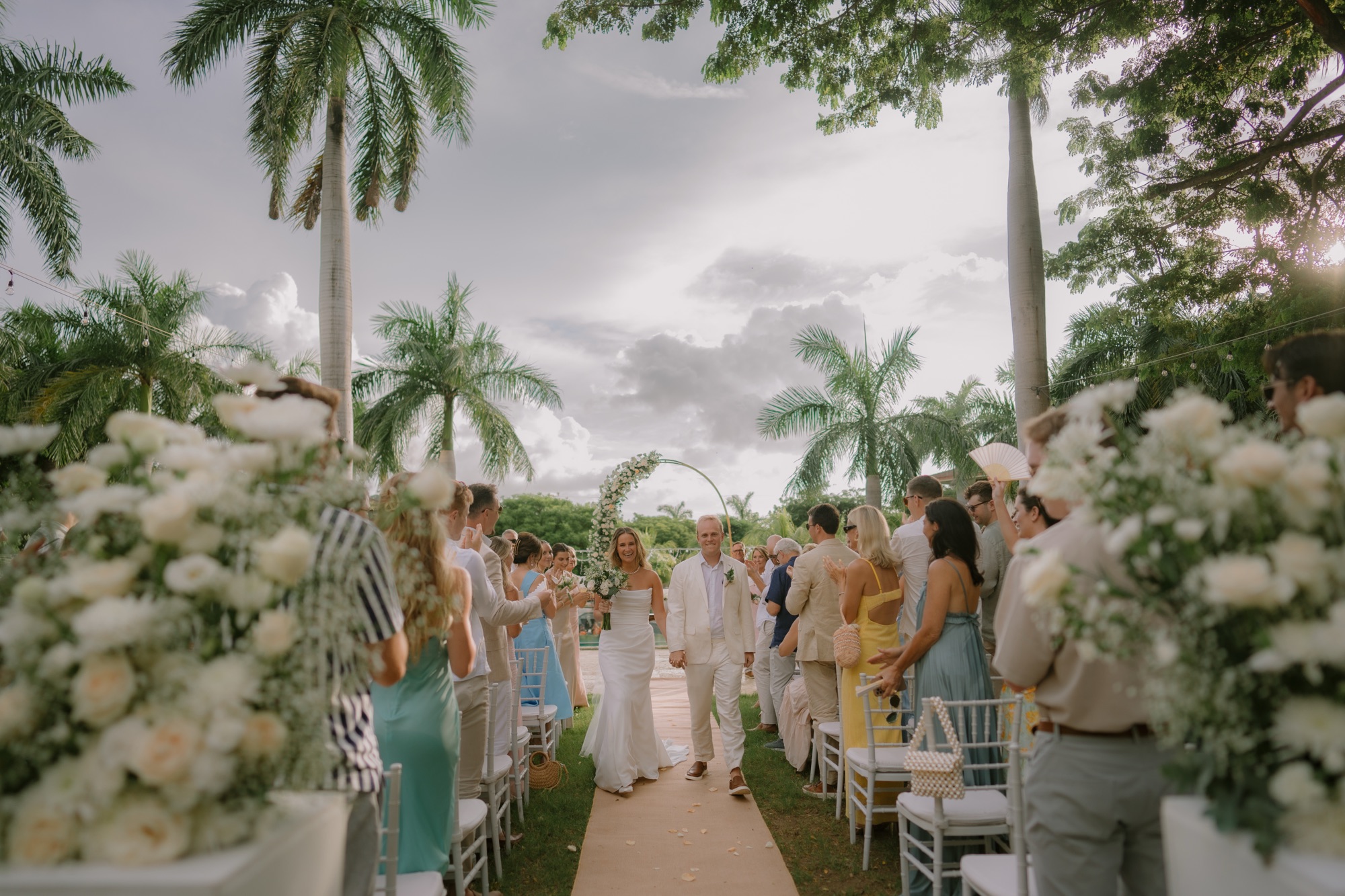 Tropical wedding with bride and groom walking down aisle